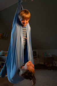 Nubbli Therapieschaukel Airy Blue – Kind liest entspannt in der Schaukel