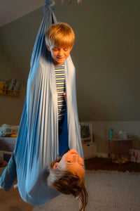Nubbli Therapieschaukel Airy Blue – Kind liest entspannt in der Schaukel