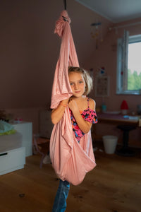 Nubbli Therapieschaukel Powder Pink im warmen Kinderzimmer